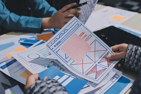 Group of young application developers analyzing uxui mobile app templates d.. Stock Photos