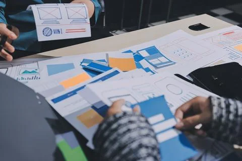 Group of young application developers analyzing uxui mobile app templates d.. Stock Photos