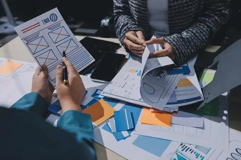 Group of young application developers analyzing uxui mobile app templates d.. Stock Photos