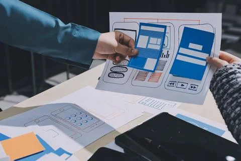 Group of young application developers analyzing uxui mobile app templates d.. Stock Photos