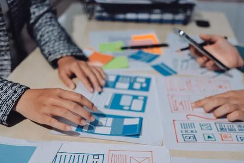 Group of young application developers analyzing uxui mobile app templates d.. Stock Photos