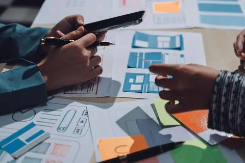 Group of young application developers analyzing uxui mobile app templates d.. Stock Photos