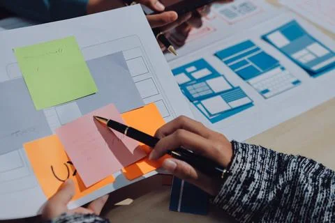 Group of young application developers analyzing uxui mobile app templates d.. Stock Photos