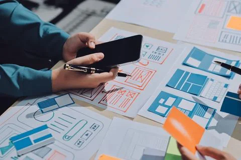 Group of young application developers analyzing uxui mobile app templates d.. Stock Photos