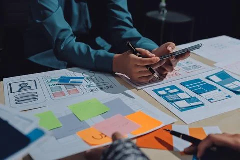 Group of young application developers analyzing uxui mobile app templates d.. Stock Photos