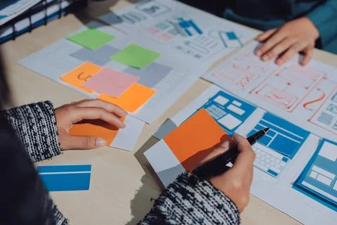 Group of young application developers analyzing uxui mobile app templates d.. Stock Photos