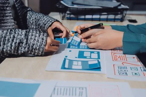 Group of young application developers analyzing uxui mobile app templates d.. Stock Photos