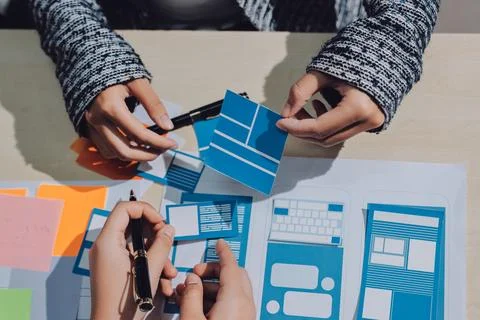 Group of young application developers analyzing uxui mobile app templates d.. Stock Photos