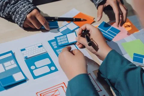 Group of young application developers analyzing uxui mobile app templates d.. Stock Photos