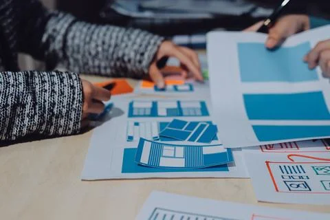 Group of young application developers analyzing uxui mobile app templates d.. Stock Photos