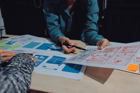 Group of young application developers analyzing uxui mobile app templates d.. Stock Photos