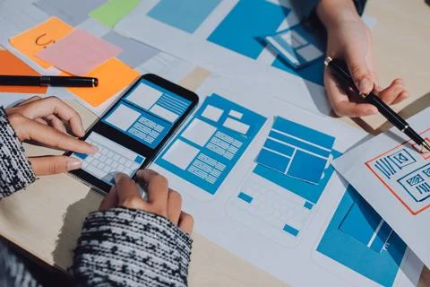 Group of young application developers analyzing uxui mobile app templates d.. Stock Photos