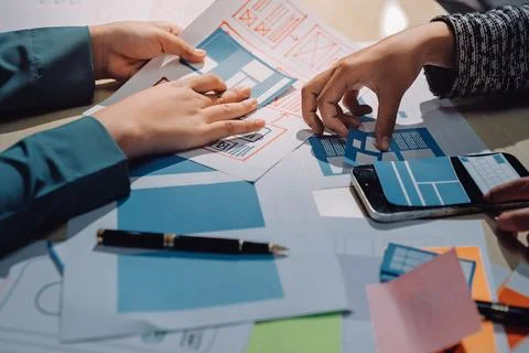 Group of young application developers analyzing uxui mobile app templates d.. Stock Photos
