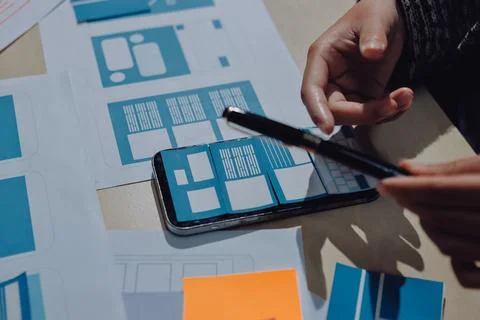 Group of young application developers analyzing uxui mobile app templates d.. Stock Photos