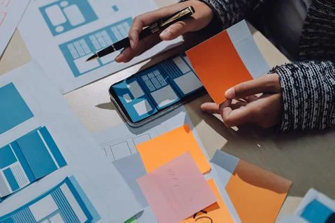 Group of young application developers analyzing uxui mobile app templates d.. Stock Photos