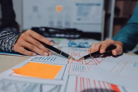 Group of young application developers analyzing uxui mobile app templates d.. Stock Photos
