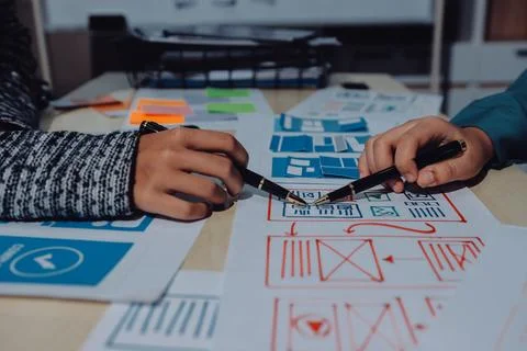 Group of young application developers analyzing uxui mobile app templates d.. Stock Photos