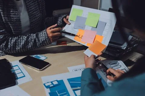 Group of young application developers analyzing uxui mobile app templates d.. Stock Photos