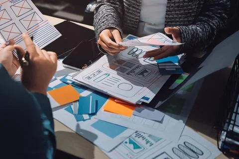 Group of young application developers analyzing uxui mobile app templates d.. Stock Photos