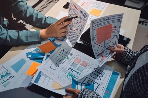 Group of young application developers analyzing uxui mobile app templates d.. Stock Photos