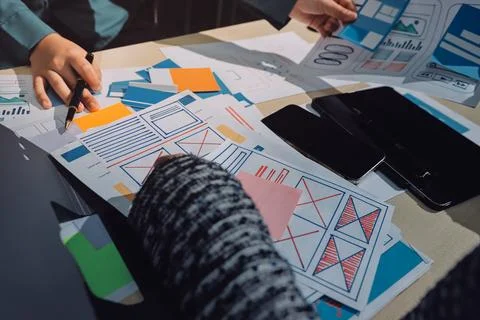Group of young application developers analyzing uxui mobile app templates d.. Stock Photos
