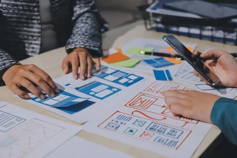 Group of young application developers analyzing uxui mobile app templates d.. Stock Photos