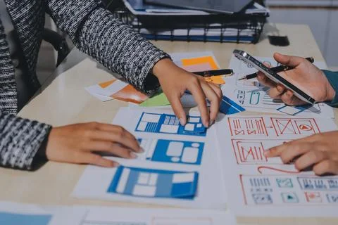 Group of young application developers analyzing uxui mobile app templates d.. Stock Photos