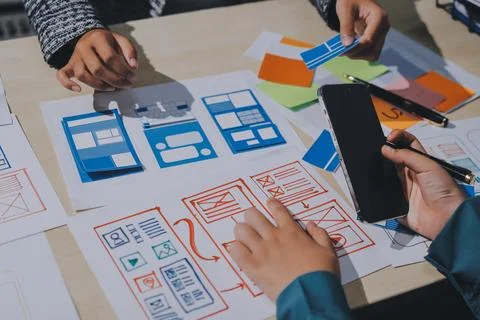Group of young application developers analyzing uxui mobile app templates d.. Foto stock