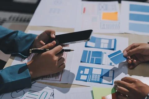 Group of young application developers analyzing uxui mobile app templates d.. Stock Photos