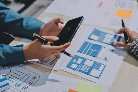 Group of young application developers analyzing uxui mobile app templates d.. Stock Photos