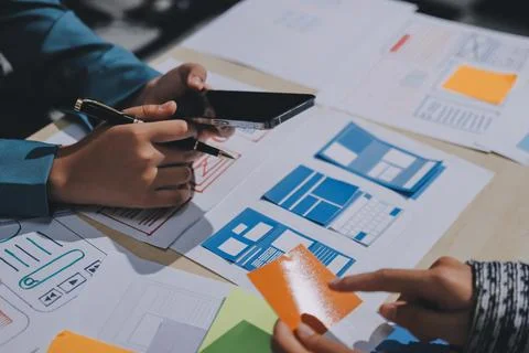 Group of young application developers analyzing uxui mobile app templates d.. Stock Photos