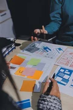 Group of young application developers analyzing uxui mobile app templates d.. Stock Photos