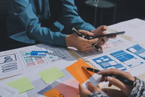 Group of young application developers analyzing uxui mobile app templates d.. Stock Photos