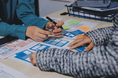 Group of young application developers analyzing uxui mobile app templates d.. Stock Photos