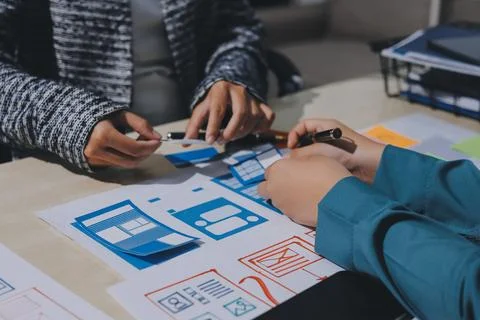 Group of young application developers analyzing uxui mobile app templates d.. Stock Photos