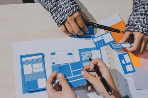 Group of young application developers analyzing uxui mobile app templates d.. Stock Photos