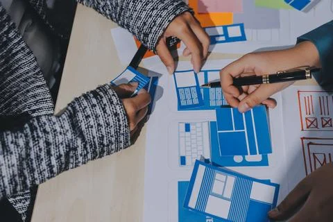 Group of young application developers analyzing uxui mobile app templates d.. Stock Photos