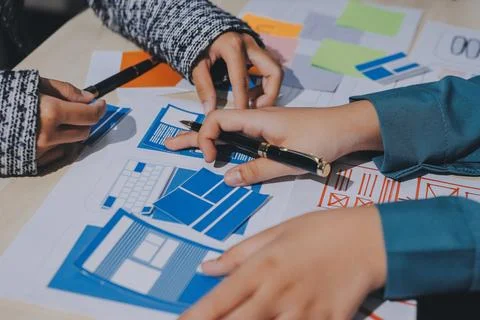 Group of young application developers analyzing uxui mobile app templates d.. Stock Photos