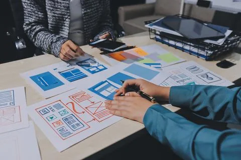 Group of young application developers analyzing uxui mobile app templates d.. Stock Photos