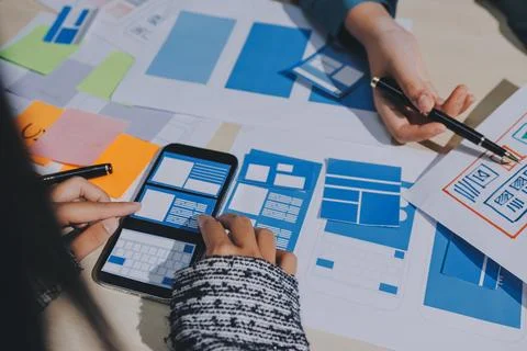 Group of young application developers analyzing uxui mobile app templates d.. Foto stock