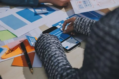 Group of young application developers analyzing uxui mobile app templates d.. Stock Photos