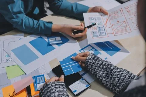 Group of young application developers analyzing uxui mobile app templates d.. Stock Photos
