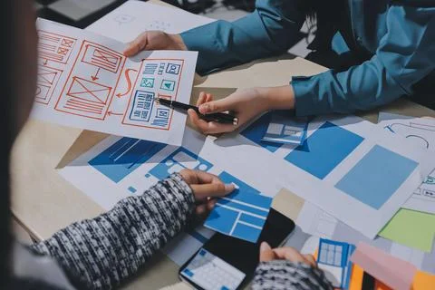 Group of young application developers analyzing uxui mobile app templates d.. Stock Photos