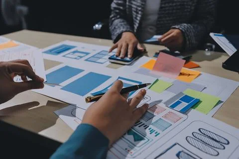 Group of young application developers analyzing uxui mobile app templates d.. Stock Photos