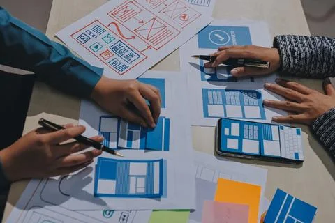 Group of young application developers analyzing uxui mobile app templates d.. Foto stock