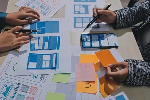 Group of young application developers analyzing uxui mobile app templates d.. Stock Photos