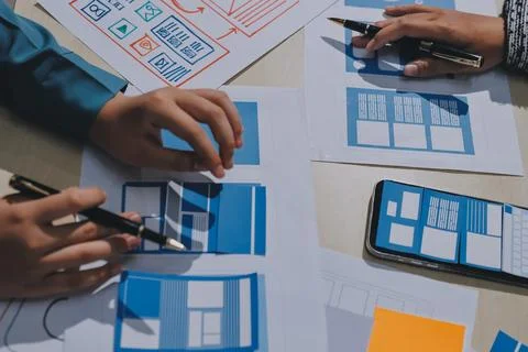 Group of young application developers analyzing uxui mobile app templates d.. Stock Photos