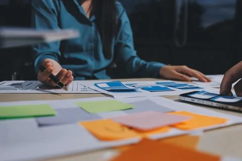 Group of young application developers analyzing uxui mobile app templates d.. Stock Photos