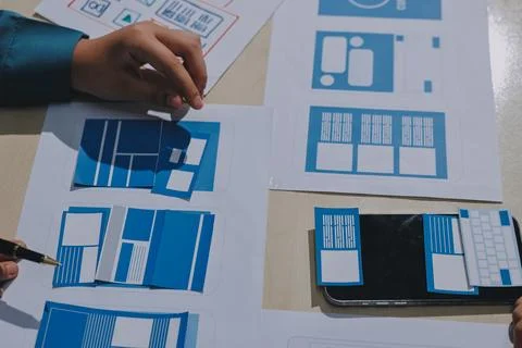 Group of young application developers analyzing uxui mobile app templates d.. Stock Photos