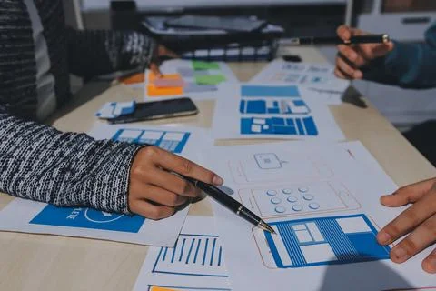 Group of young application developers analyzing uxui mobile app templates d.. Stock Photos